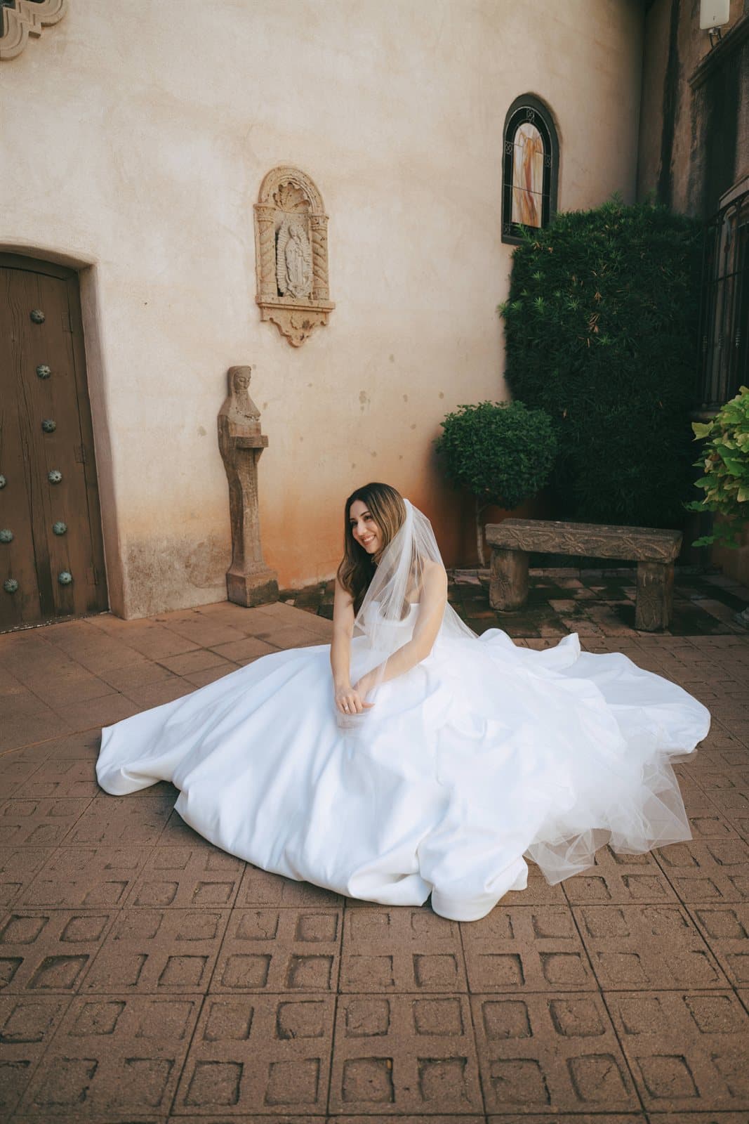 A bride seated with her gown spread across a Tlaquepaque courtyard