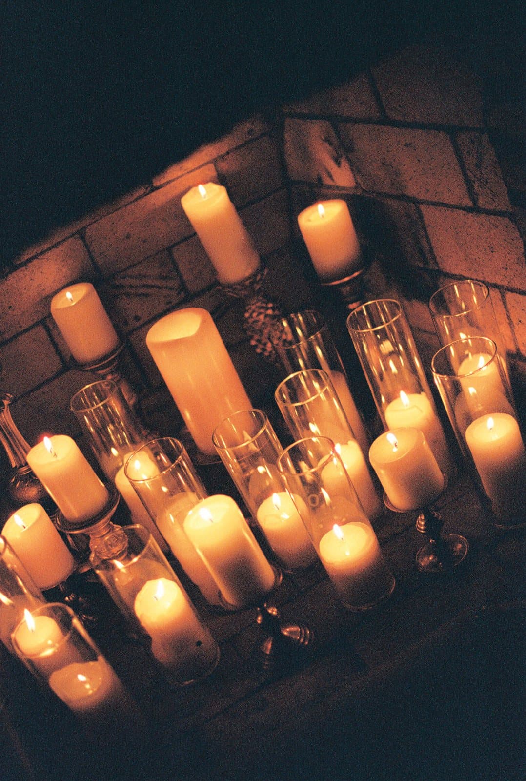 Dozens of candles glowing in a brick fireplace